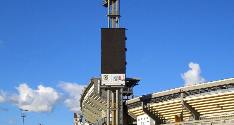 Fachada exterior del Estadio El Campín en Bogotá, con la torre de iluminación y la graderia amarilla