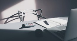 Calculadora, cuaderno con anotaciones y un portátil sobre un escritorio, con luz de ventana