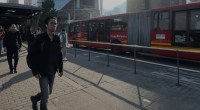 Bus articulado rojo de TransMilenio junto a la estación temporal Calle 57, con peatones en la acera
