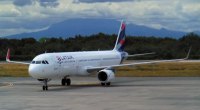 Avión blanco de LATAM, con la cola en azul y rojo, rodando por una pista de aeropuerto