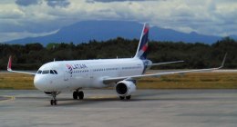 Avión blanco de LATAM, con la cola en azul y rojo, rodando por una pista de aeropuerto