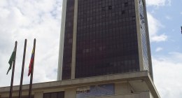 Edificio torre del Banco de la República en Medellín, con banderas y una escultura de bronce al pie