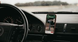 Celular con una app de navegación sujeto en el tablero de un carro, con la carretera al fondo