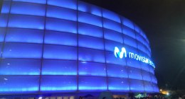 Movistar Arena de Bogotá iluminado de azul de noche, con público a la entrada de un concierto