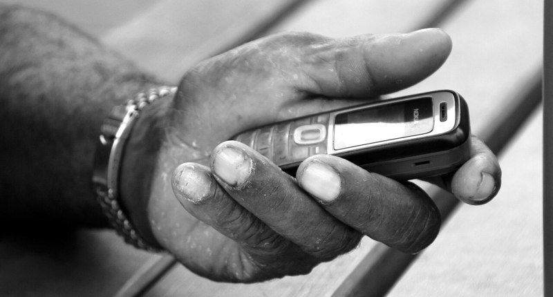 Mano sosteniendo un teléfono celular en blanco y negro