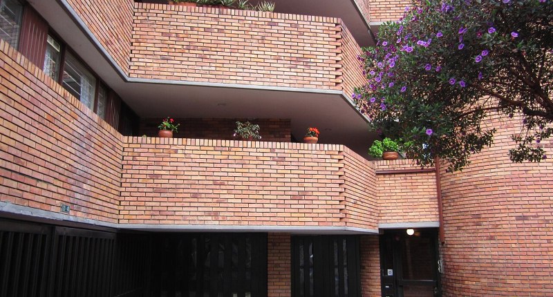 Fachada de ladrillo de un conjunto residencial en Bogotá, con balcones y plantas