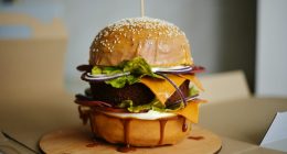 Hamburguesa con pan de semillas, queso, lechuga y cebolla morada sobre una tabla de madera