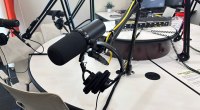 Micrófono dinámico de estudio sobre un brazo articulado, con audífonos, en una mesa redonda de un estudio de podcast