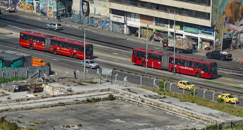 Buses articulados de TransMilenio circulando por una avenida de Bogotá, vistos desde arriba