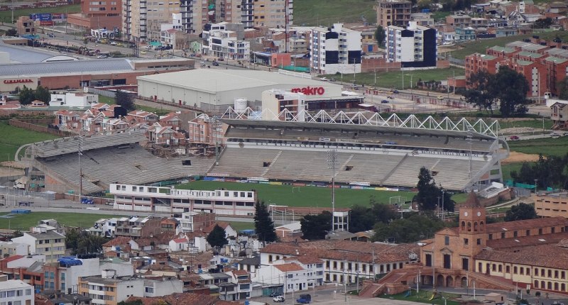 Vista aérea del estadio La Independencia de Tunja, con la cancha verde y la tribuna cubierta, rodeado de la ciudad