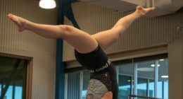 Gimnasta en equilibrio invertido sobre la barra de equilibrio