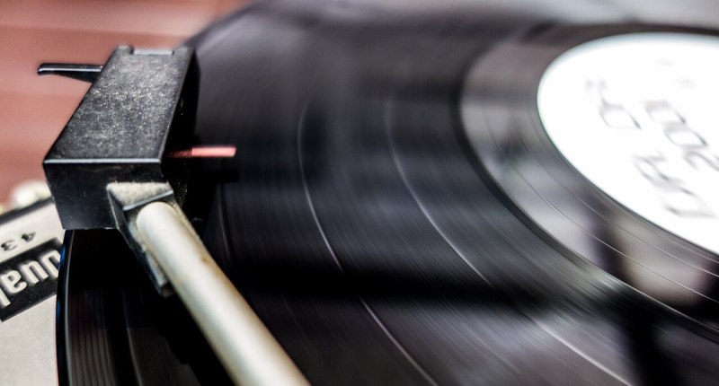 Brazo de un tocadiscos sobre un disco de vinilo negro que gira
