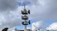 Torre de telecomunicaciones de metal blanco con antenas parabólicas y cielo nublado al fondo